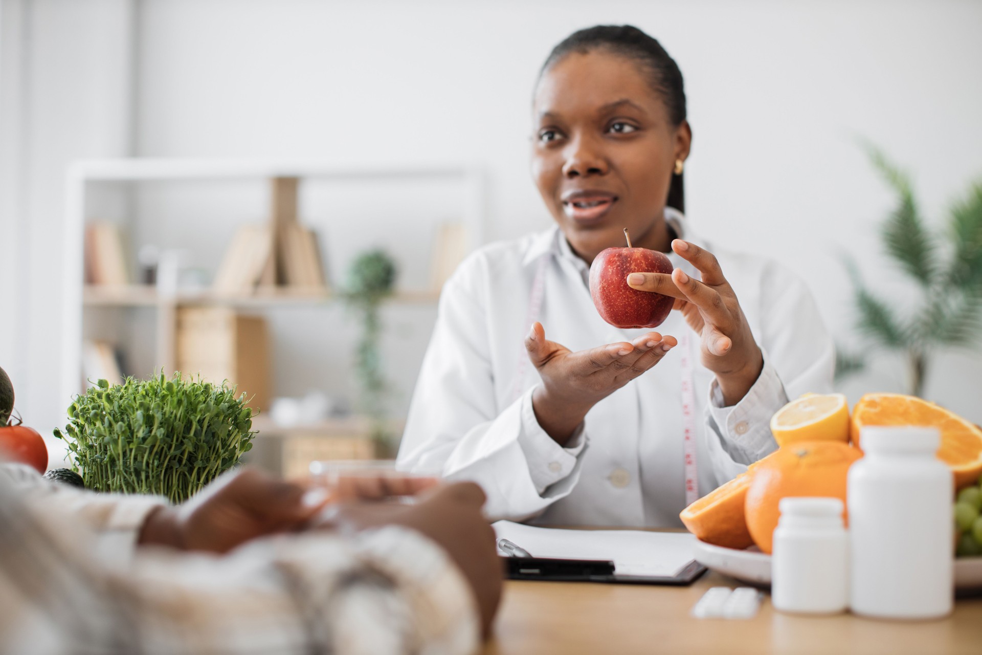 Female with apple and measuring tape talking to patient